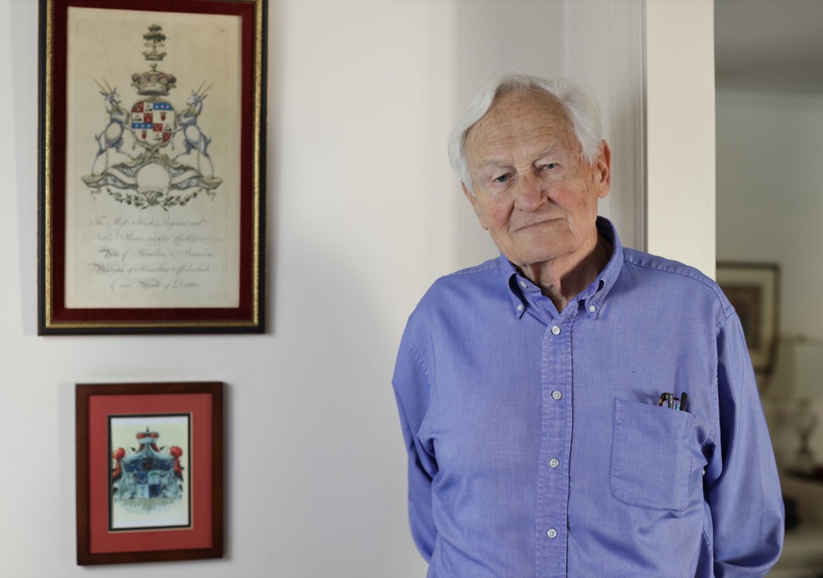 Alexander Kugushev at home, beside the family coats of arms